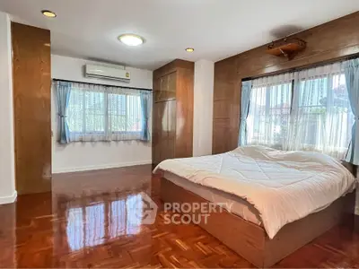 Spacious bedroom with wooden flooring and large windows for natural light