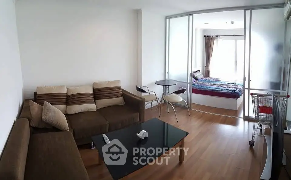 Modern studio apartment with cozy living area and bedroom separated by glass partition.