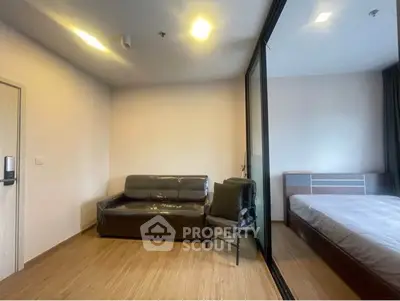 Modern studio apartment with cozy living area and bedroom separated by glass partition.