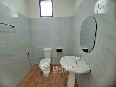 Modern bathroom with sleek fixtures and natural light, featuring a round mirror and elegant tile design.