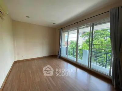Spacious empty room with large windows and balcony overlooking greenery, perfect for customization.