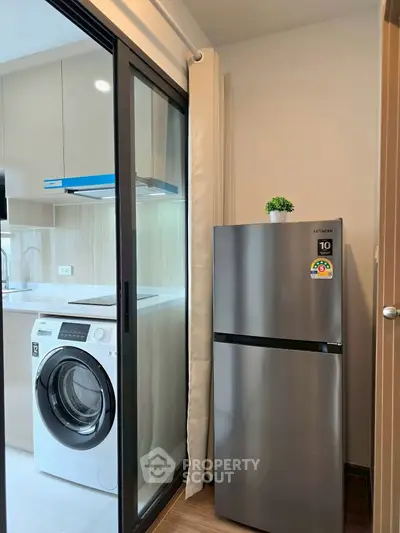 Modern kitchen with sleek appliances including a washing machine and stainless steel fridge, perfect for urban living.