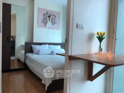 Cozy bedroom with wooden flooring, stylish wall art, and a charming vase of tulips on a shelf.