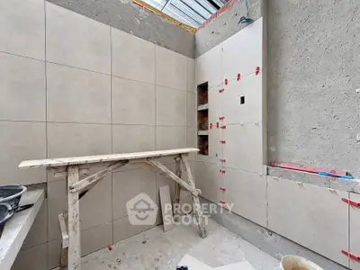 Under-construction bathroom with tiled walls and wooden scaffolding