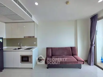 Modern apartment interior with sleek kitchen and cozy living area featuring a stylish sofa.