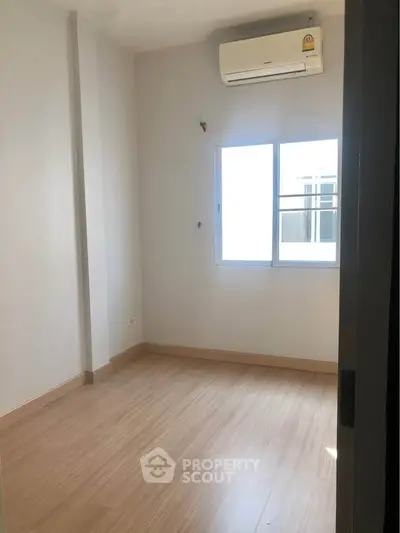 Bright empty room with wooden flooring and air conditioning, perfect for customization.