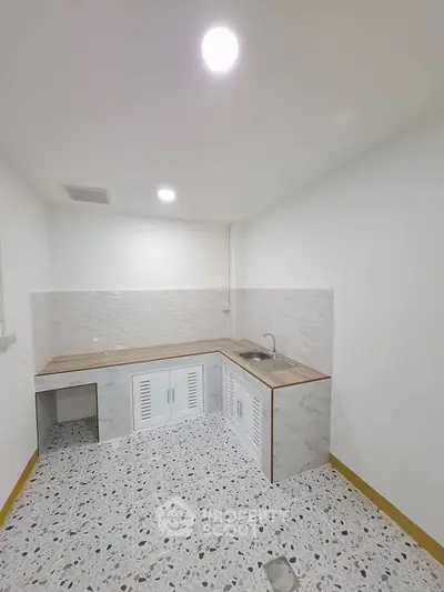 Minimalist kitchen with terrazzo flooring and wooden countertop in a compact layout.