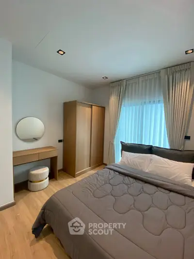 Modern bedroom with stylish decor, featuring a cozy bed, elegant curtains, and a sleek wardrobe.