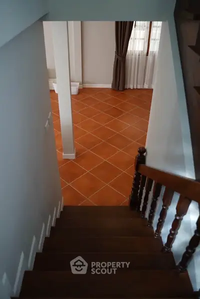 Charming staircase leading to a spacious terracotta-tiled living area with natural light.