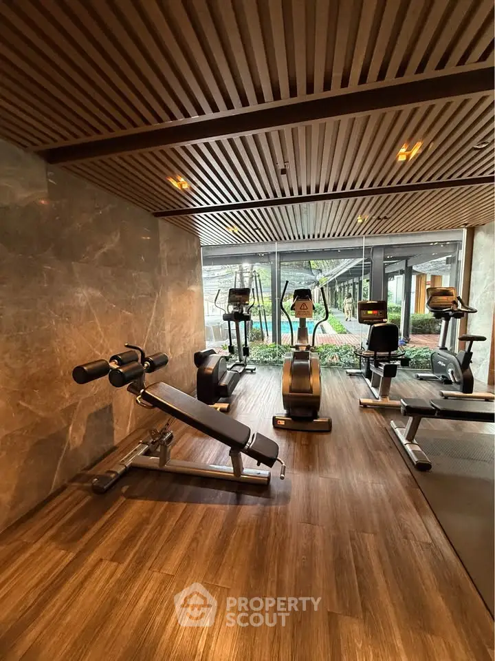 Luxurious gym with modern equipment and stunning garden view in upscale residential building.