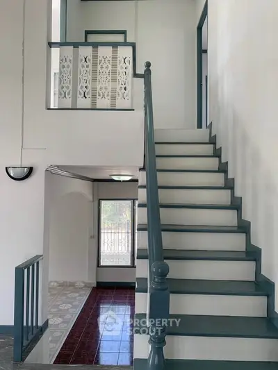 Charming interior staircase with elegant railing and bright natural light.
