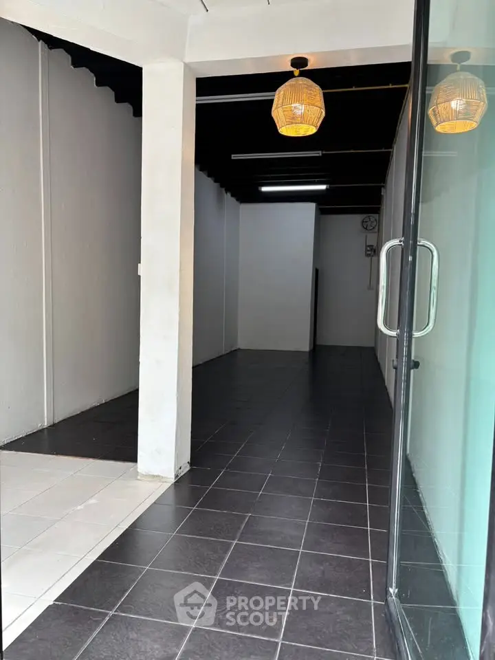 Spacious commercial space with modern lighting and glass door entrance, ideal for retail or office use.