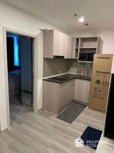 Modern kitchen with sleek cabinetry and Samsung refrigerator in a cozy apartment setting.