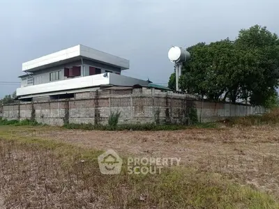 Modern two-story building with spacious yard and water tank, ideal for residential or commercial use.