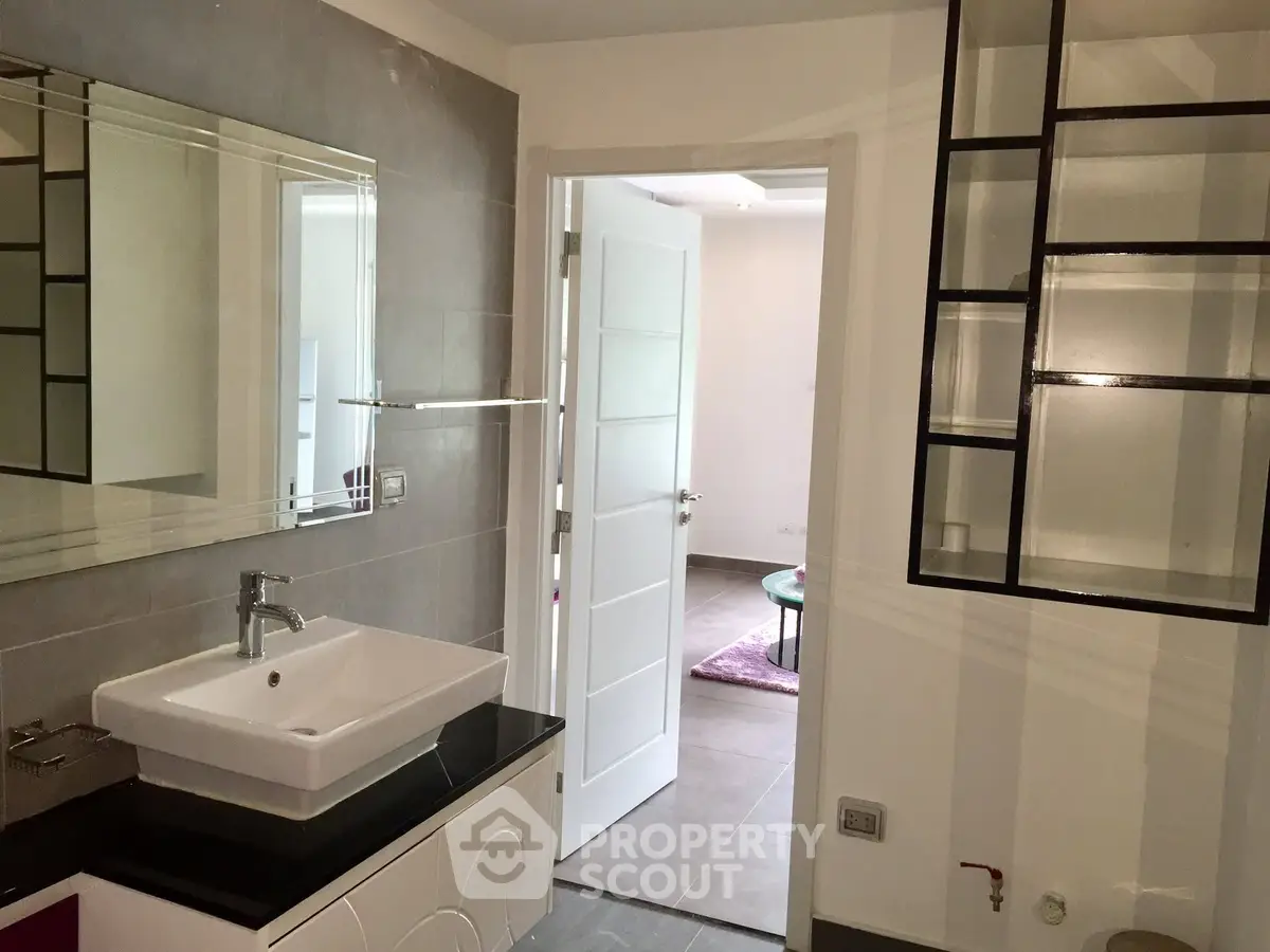 Modern bathroom with sleek sink and open door to living area
