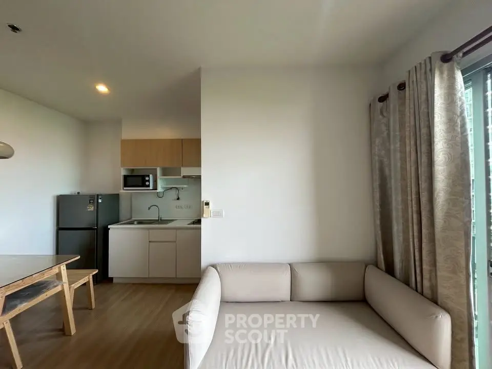 Modern apartment interior with cozy living room and compact kitchen featuring sleek appliances.