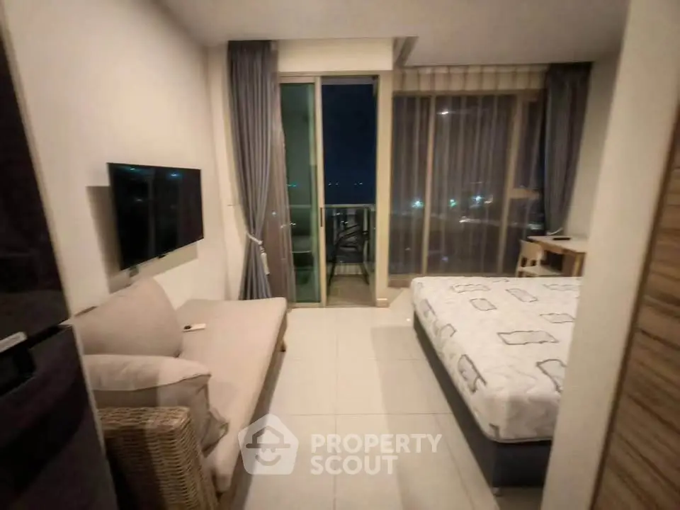 Modern bedroom with balcony view, featuring cozy bed and wall-mounted TV for ultimate relaxation.