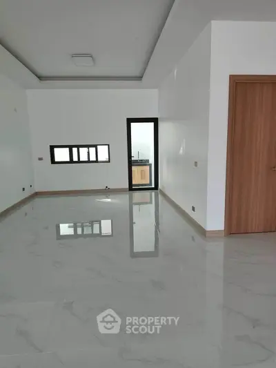 Spacious modern living room with marble flooring and large windows for natural light.
