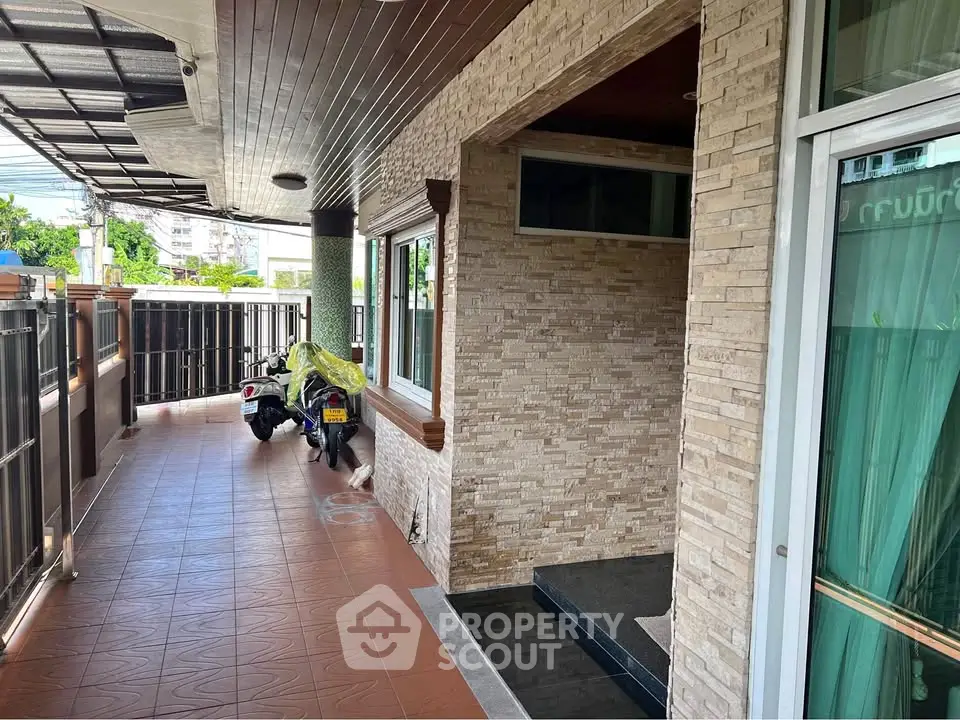 Charming covered entrance with tiled flooring and stone wall accents in a modern home.
