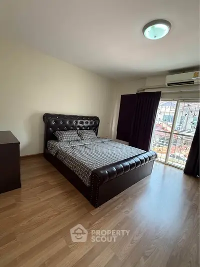 Spacious bedroom with elegant leather bed and large window for natural light.