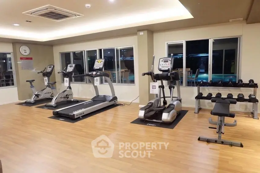 Modern gym with exercise equipment and wooden flooring in a residential building.