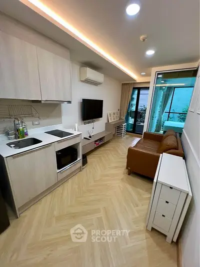 Modern living room with open kitchen and balcony access, featuring sleek design and cozy ambiance.