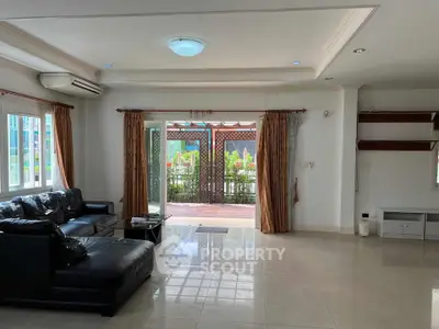 Spacious living room with leather sofa and large windows opening to a patio, perfect for entertaining.