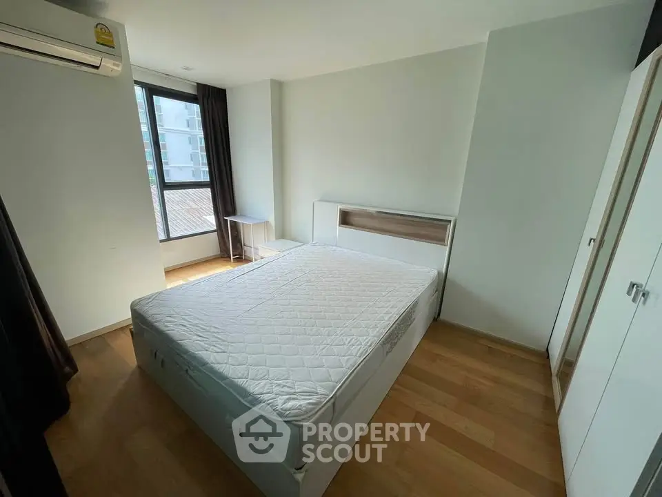 Spacious bedroom with large window and modern furnishings in a bright apartment.