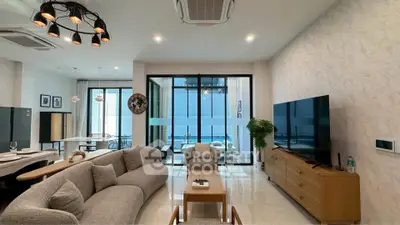 Spacious modern living room with elegant decor and large glass doors leading to a balcony.
