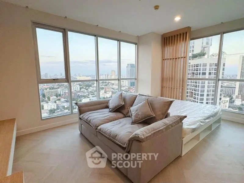 Modern living room with panoramic city view and cozy sofa in high-rise apartment.
