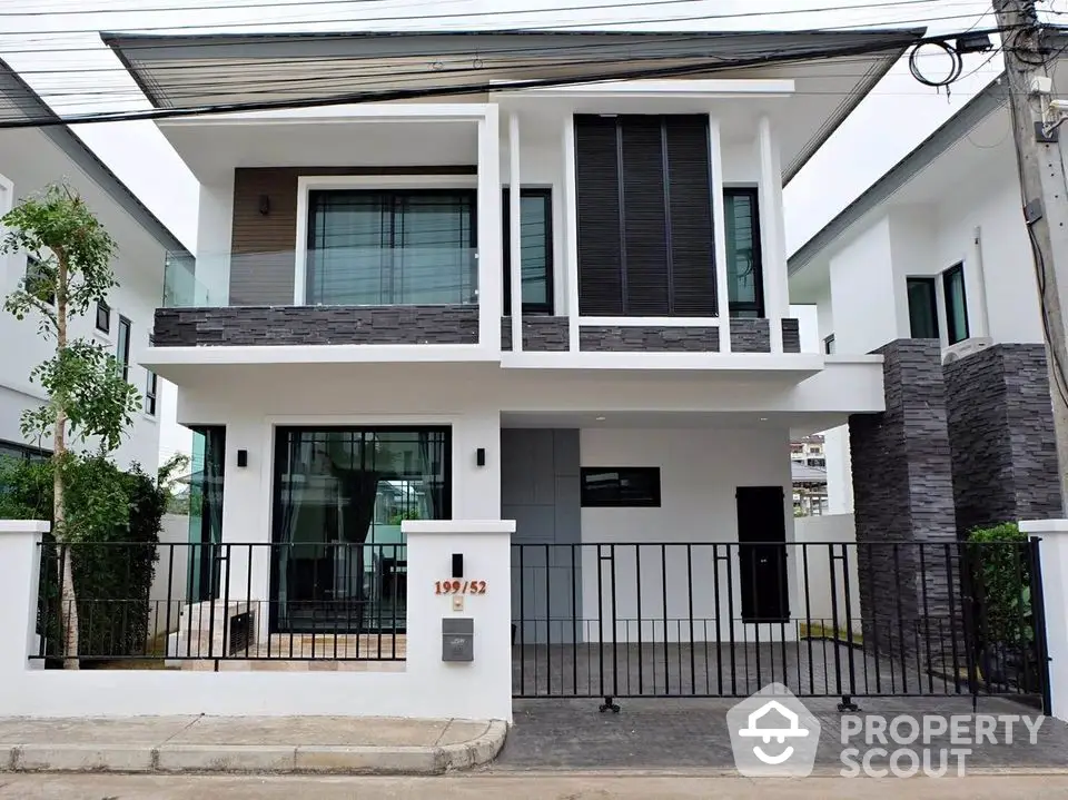 Modern two-story house with sleek design and gated entrance in suburban neighborhood.