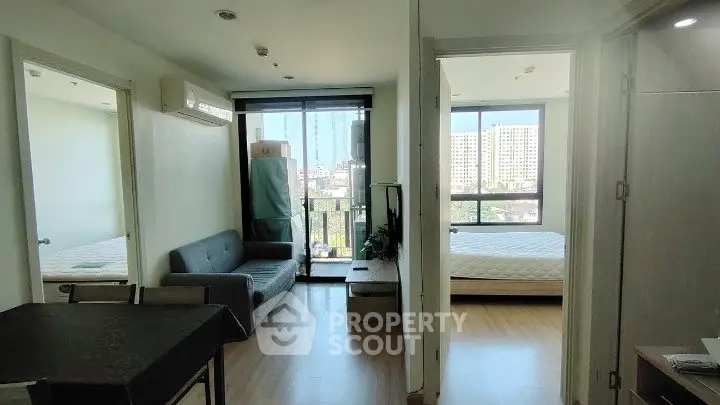 Modern apartment interior with cozy living room and two bedrooms, featuring large windows and natural light.