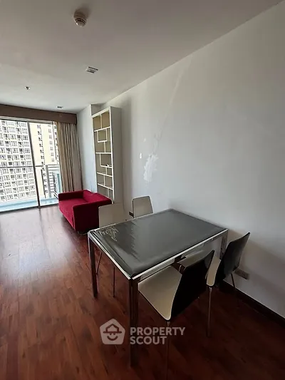 Modern living room with red sofa and dining table, featuring large windows and wooden flooring.