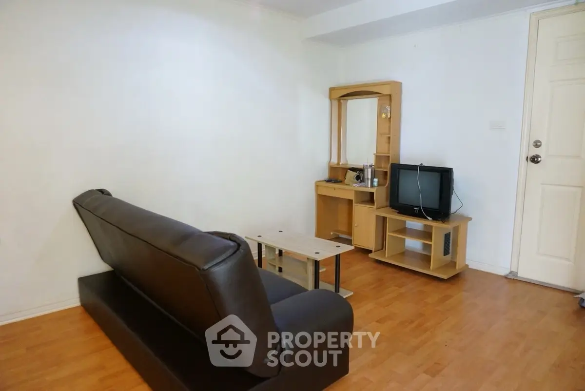 Cozy living room with leather sofa and wooden TV stand, perfect for relaxation.