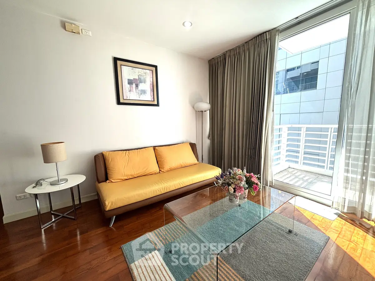 Bright living room with modern decor, glass coffee table, and balcony access in a stylish apartment.
