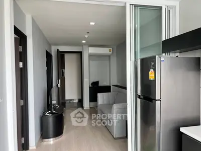 Modern apartment interior with sleek kitchen and cozy living area, featuring a stylish fridge and air conditioning.