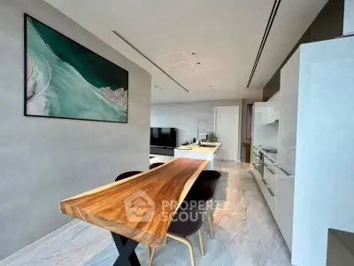 Modern open-plan kitchen and dining area with sleek design and wooden table.