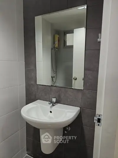 Modern bathroom with sleek sink and mirror, featuring a shower area with contemporary design.