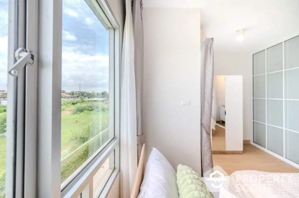 Bright bedroom with large window offering scenic views and modern sliding closet doors.