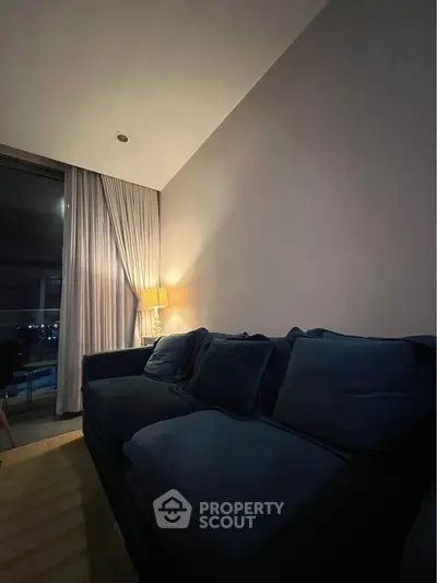 Cozy living room with plush blue sofa and ambient lighting, perfect for relaxation.