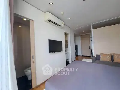 Modern bedroom with air conditioning and wall-mounted TV, featuring a sleek ensuite bathroom.