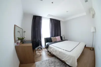Cozy bedroom with modern decor, featuring a comfortable bed, stylish curtains, and wooden flooring.