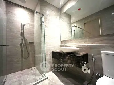 Modern bathroom with glass shower and sleek fixtures in luxury apartment.