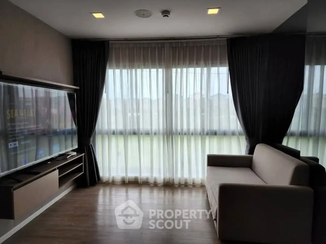 Modern living room with large TV and cozy sofa, featuring floor-to-ceiling windows and elegant curtains.