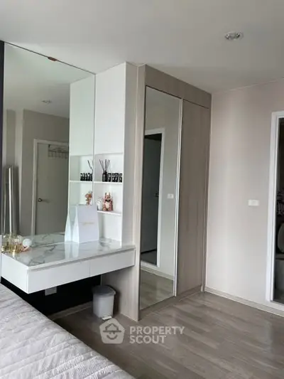 Modern bedroom with mirrored wardrobe and sleek vanity in stylish apartment.