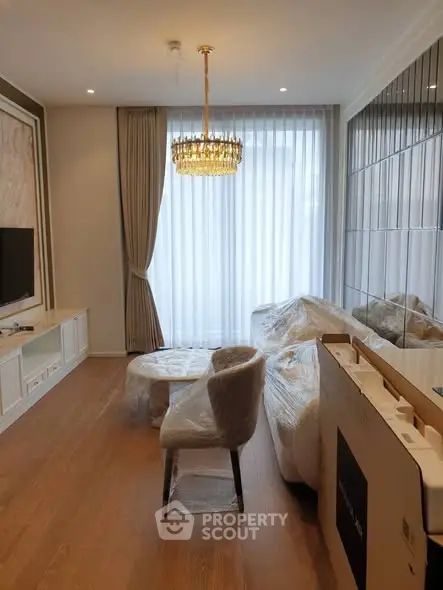 Elegant living room with chandelier and modern decor, featuring floor-to-ceiling windows and stylish furniture.
