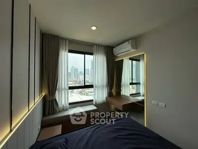 Modern bedroom with city view and stylish lighting in urban apartment.