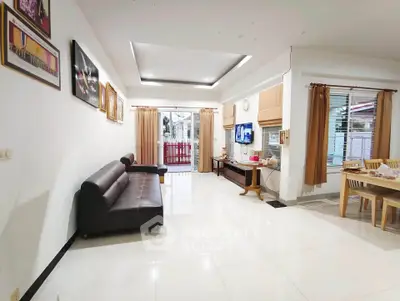 Spacious living room with modern decor and open dining area, featuring sleek furniture and ample natural light.