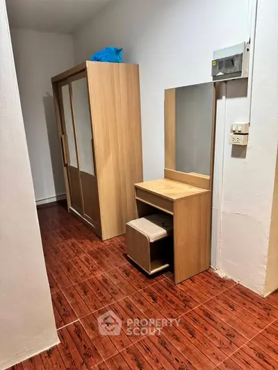 Cozy bedroom corner with wooden wardrobe and vanity set on polished wooden floor.