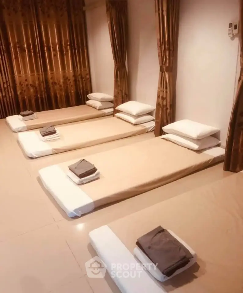 Spacious room with multiple floor mattresses and elegant curtains, ideal for shared living or guest accommodation.